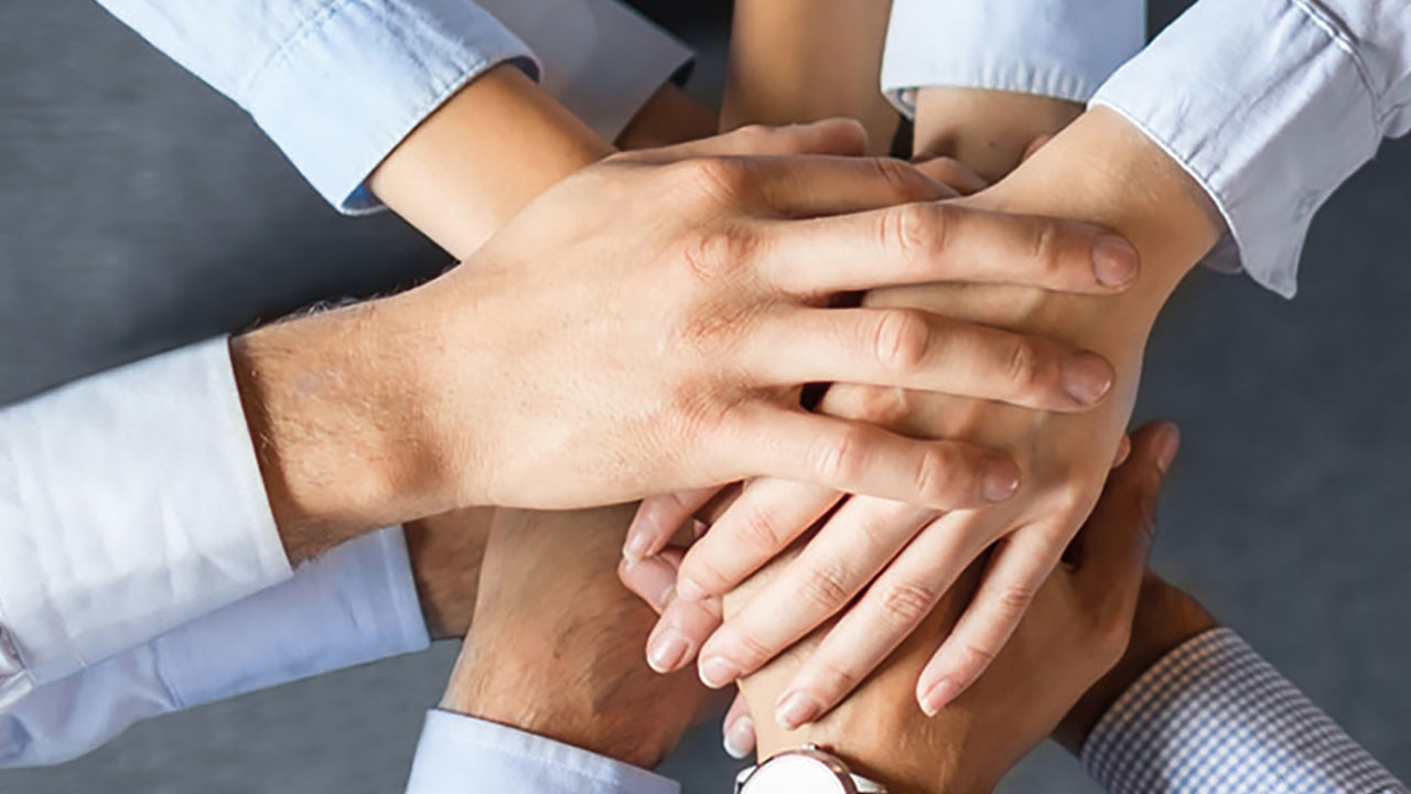 Mehrere Hände liegen aufeinander.
