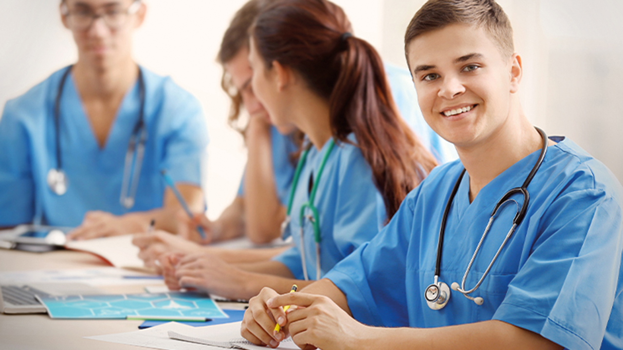 Junges Pflegepersonal sitzt zu einer Besprechung an einem Tisch.