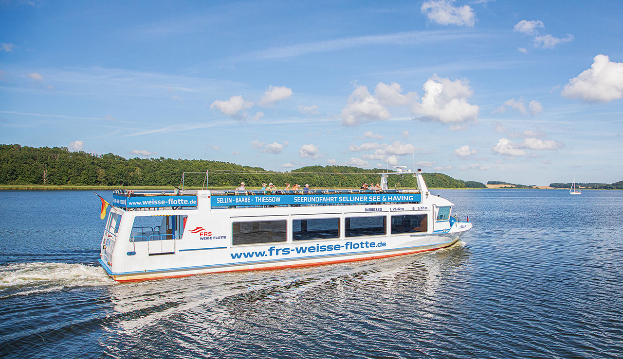 Ein Schiff mit der Aufschrift "www.frs-weisse-flotte.de" fährt im Wasser.