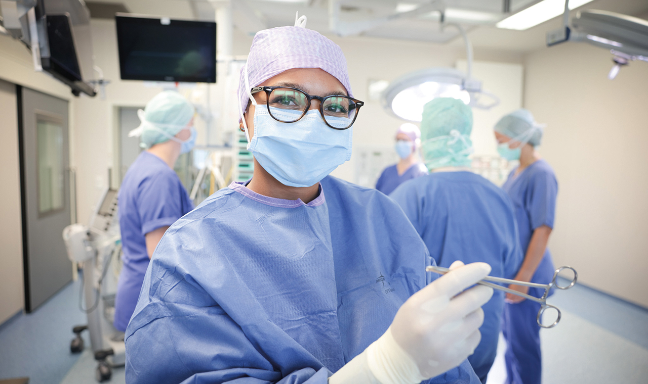 Medizinische Mitarbeiterin in OP Kleidung und Maske.