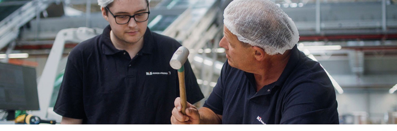 Zwei Personen in dunklen Poloshirts und Haarhauben