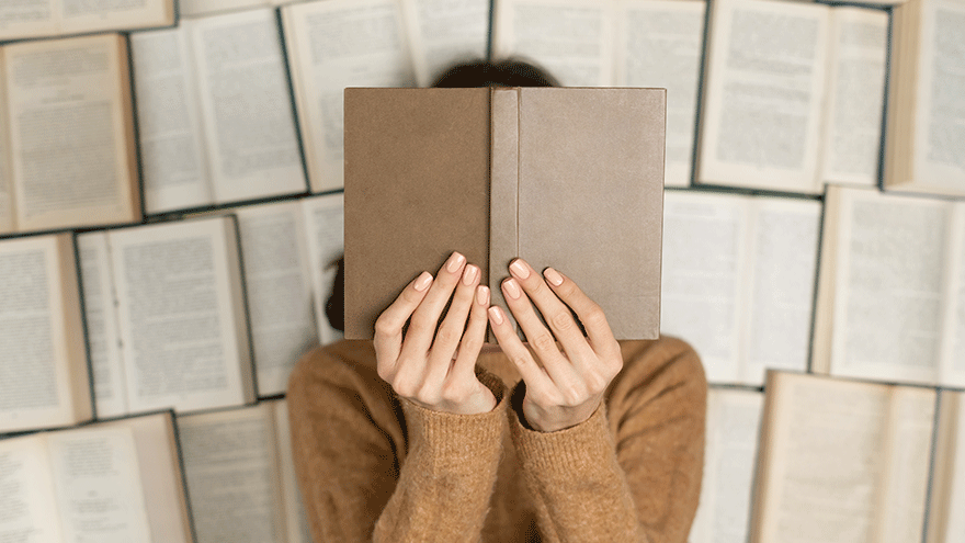 Leserin auf Büchern (Symbolbild). Bild von kroshka__nastya auf Freepik.
