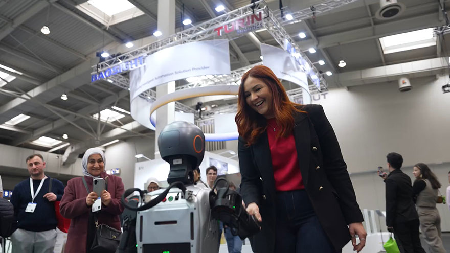 Messebesucherin wendet sich einem Roboter zu. 