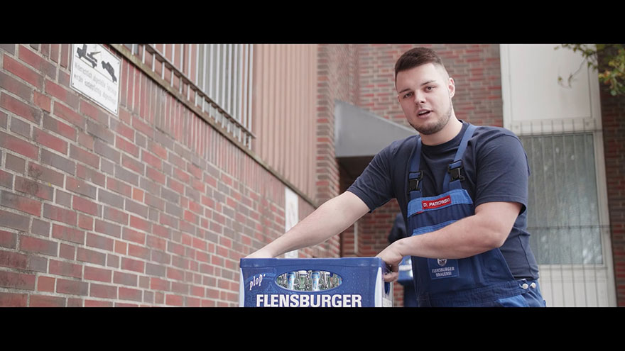 Auszubildender der Flensburger Brauerei trägt Bierkasten.