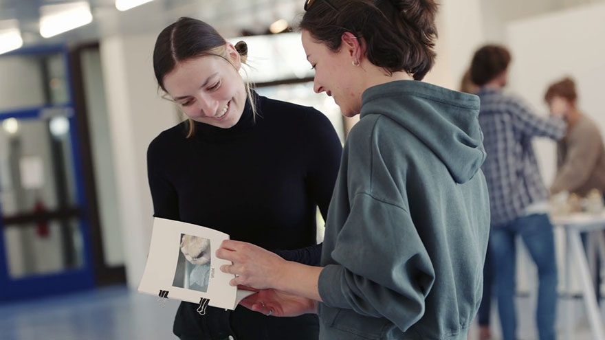 Zwei Studierende schauen sich gemeinsam Infomaterial an. 
