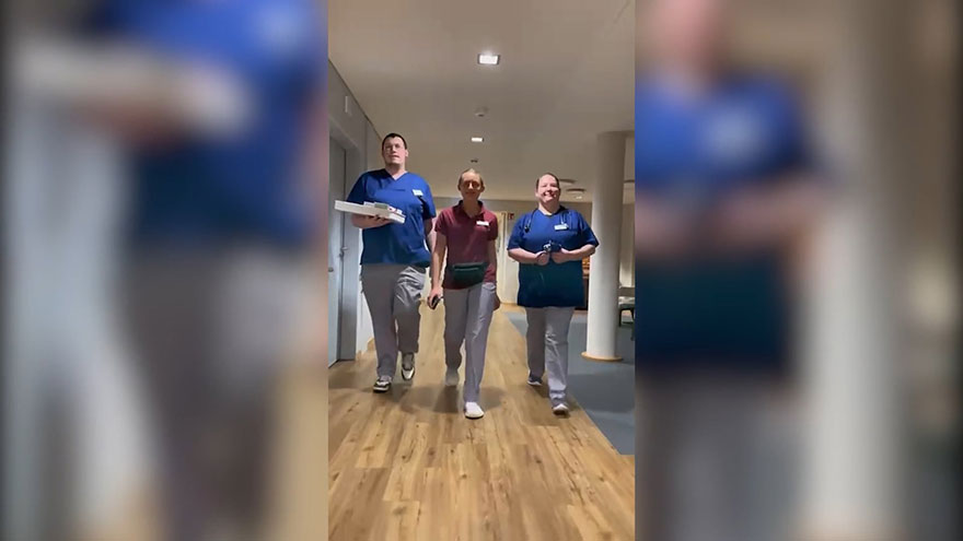 Drei Pflege-Azubis laufen durch Gang einer Pflegeinrichtung.