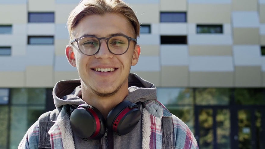 Auszubildender der Firma REYHER vor einem Gebäude.