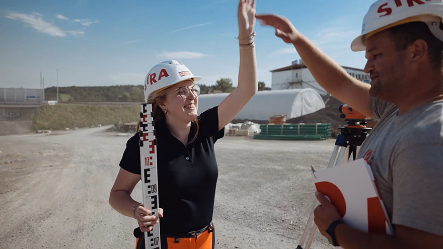 STRABAG-Mitarbeitende auf einer Baustelle klatschen sich Hände ab.
