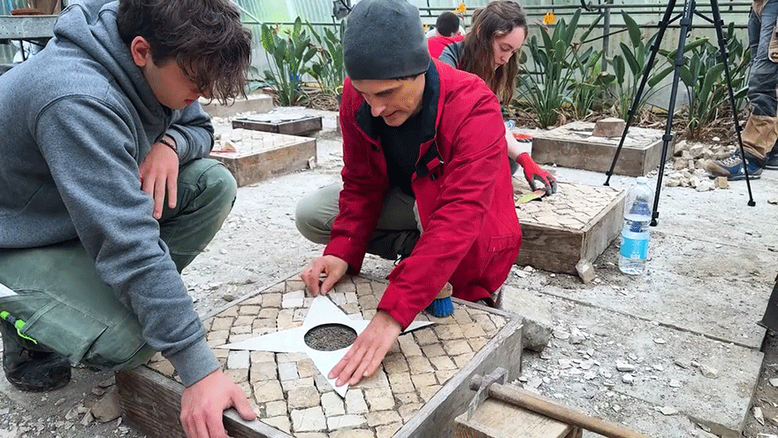 Auszubildende und Ausbilder beim Erstellen kunstvoller Straßenpflaster mithilfe einer Form.