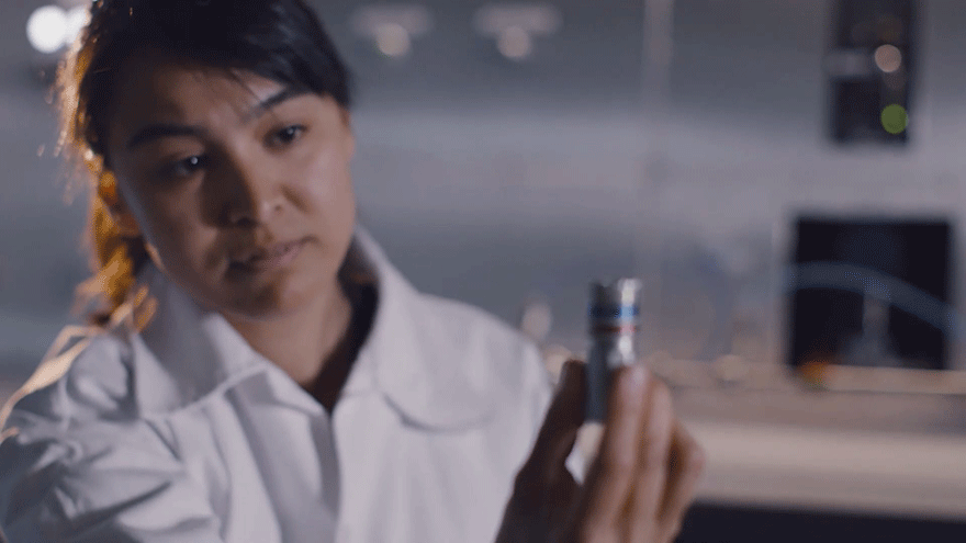 CEJN-Mitarbeiterin schaut sich Schnellverschlusskupplungsteil in ihrer Hand haltend an.